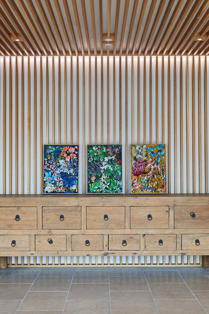 Framed trio of metal artworks against wooden backdrop.