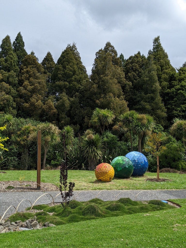 three orb sculpture made from repurposed 44-gallon drums against native NZ bush